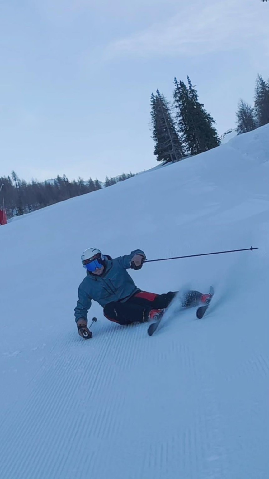 Riccardo carving a turn on a groomed slope, hip almost touching the snow.